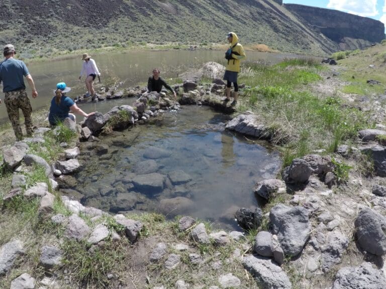 People soaking in hot springs on Owyhee River after white water rafting