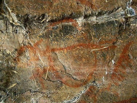 Petroglyphs on a rock wall in a cave.