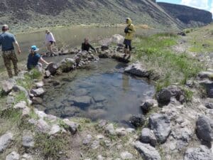 People soaking in hot springs on Owyhee River after white water rafting